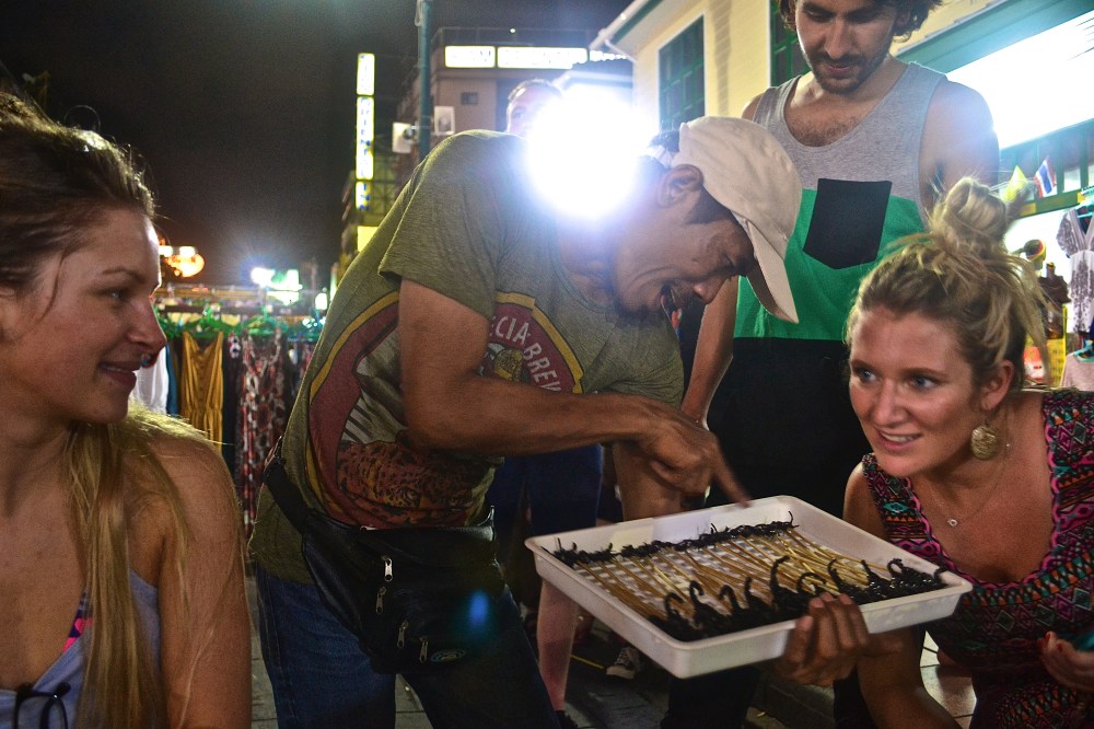 A tourist being offered scorpions by a local 